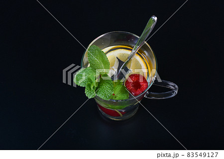 fresh drink with lemon, raspberries and green mint on black background 83549127