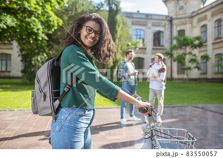 A smiling young mulatta riding a bike and feeling cheerful A smiling young mulatta riding a bike and feeling cheerful 83550057