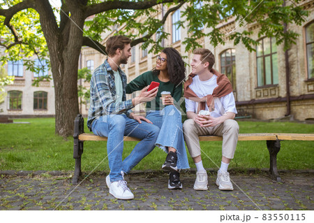 Three friends spending time in the park and talking Three friends spending time in the park and talking 83550115