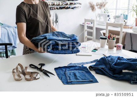 Denim Upcycling Ideas, Using Old Jeans, Repurposing Jeans, Reusing Old Jeans, Upcycle Stuff. Woman seamstress holding Stack of old blue jeans in sewing studio. 83550951