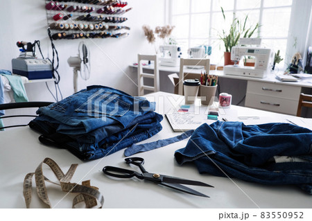 Denim Upcycling Ideas, Using Old Jeans, Repurposing Jeans, Reusing Old Jeans, Upcycle Stuff. Stack of old blue jeans, scissors, thread and sewing tools in sewing studio. Selective focus Denim Upcycling Ideas, Using Old Jeans, Repurposing Jeans, Reusing Old Jeans, Upcycle Stuff. Stack of old blue jeans, scissors, thread and sewing tools in sewing studio. Selective focus 83550952