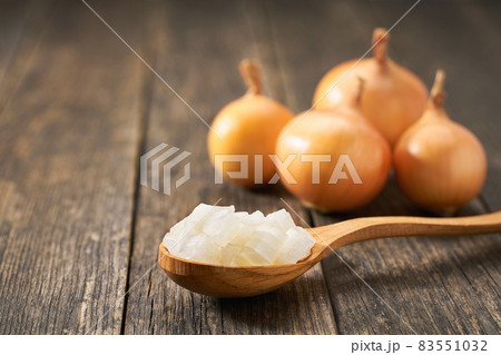 Chopped onion in a wooden spoon on a rustic table, copy space for text. Chopped onion in a wooden spoon on a rustic table, copy space for text. 83551032