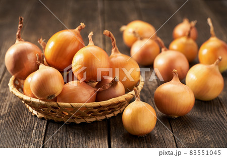 yellow onions in a basket on a wooden table. 83551045