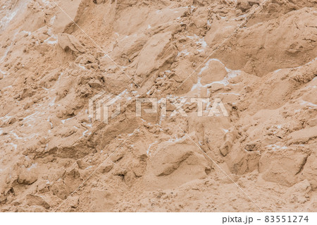 A large pile of sand of natural industrial material is stored outdoors on the territory of the plant 83551274