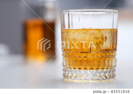 Glass of whiskey with ice standing on table closeup Glass of whiskey with ice standing on table closeup 83551916