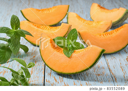 Sliced ripe cantaloupe melon and fresh mint on a wooden table. Sliced ripe cantaloupe melon and fresh mint on a wooden table. 83552089