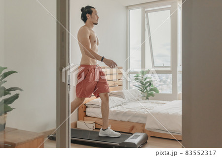 Man exercise by walking on the treadmill in his apartment. Man exercise by walking on the treadmill in his apartment. 83552317