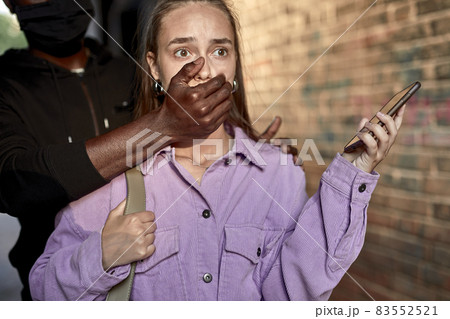 Criminal stalking woman alone in a dark street alley, closing her mouth, ask to keep silence 83552521