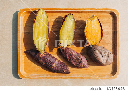 Sweet potato cut into half on wooden plate. 83553098