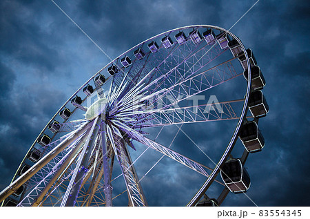 Big luminous ferris wheel in front of dark blue dramatic sky 83554345
