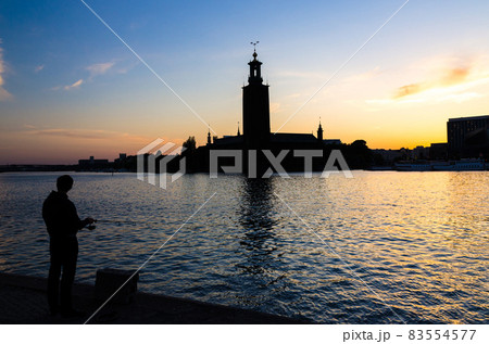 Silhouette of fisherman with pole and Stockholm City Hall, Sweden 83554577