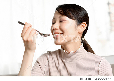 スプーンで食事をする若い黒髪の女性 スプーンで食事をする若い黒髪の女性 83555477