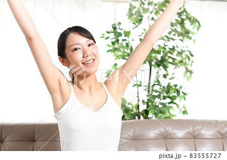バンザイをする若いノースリーブ姿の若い女性 83555727