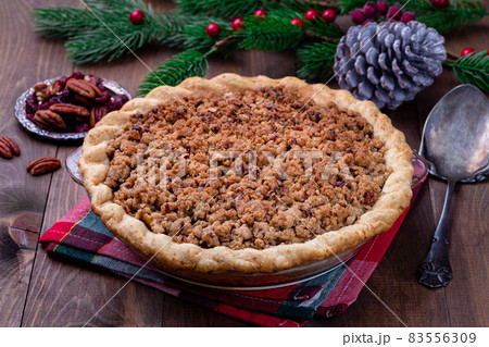 Freshly baked American apple cranberry pie, topped with crumbled dough and pecan, in baking dish Freshly baked American apple cranberry pie, topped with crumbled dough and pecan, in baking dish 83556309
