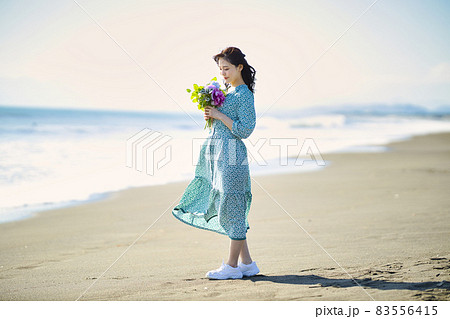 砂浜を歩く若い女性 83556415