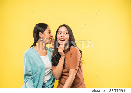 woman surprised when her friend talks whispering in her ear with copyspace woman surprised when her friend talks whispering in her ear with copyspace 83556914