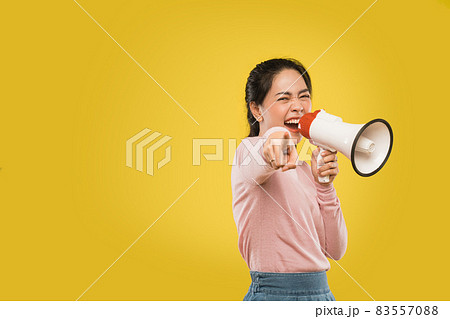 Excited beautiful woman talking seriously holding megaphone and finger pointing 83557088