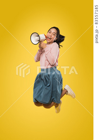 Cute girl jumping and screaming making announcement using megaphone 83557185