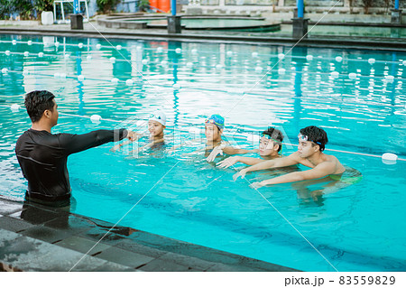 an instructor in the pool pointing while lecturing four teenagers 83559829
