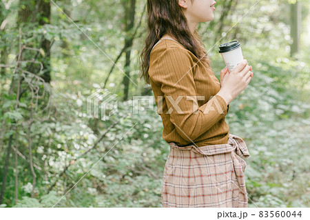 自然に囲まれコーヒーを飲む女性　自然の中で休憩する人 83560044
