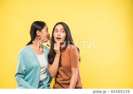 woman surprised when her friend talks whispering in her ear with copyspace woman surprised when her friend talks whispering in her ear with copyspace 83560159