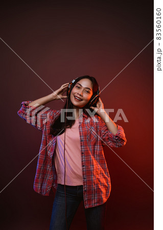 cheerful girl enjoying music using headphones with two hands holding headphones cheerful girl enjoying music using headphones with two hands holding headphones 83560160