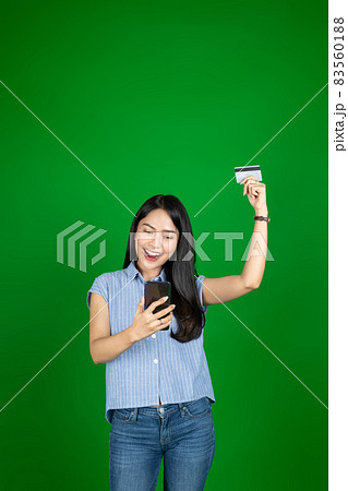 excited asian woman using a mobile phone while holding atm card with raised hand 83560188