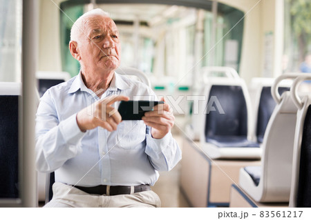 Senior European man with smartphone in tram 83561217