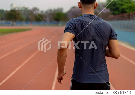 Sports and recreation concept a young male adult running in low speed in the sports stadium as his healthy routine in the evening Sports and recreation concept a young male adult running in low speed in the sports stadium as his healthy routine in the evening 83561314