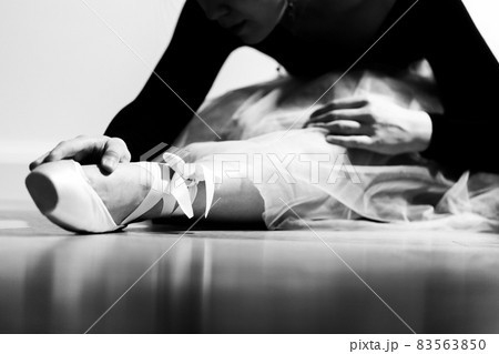A ballerina in pointe is stretched before the performance. Black and white photo. 83563850