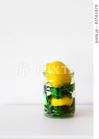 Yellow lemon and green mint in a transparent jar on a white background, Front view. Copy space. Yellow lemon and green mint in a transparent jar on a white background, Front view. Copy space. 83563879