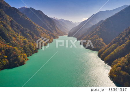 紅葉に包まれた高瀬ダムの美しいエメラルドグリーンの湖面　長野県大町市（ドローンによる空撮） 83564517