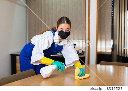 Portrait of a young woman worker in a protective mask, washing an office desk Portrait of a young woman worker in a protective mask, washing an office desk 83565274