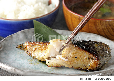 脂が乗って美味しそうな焼き目のついた銀鱈の西京焼きとほかほかご飯と熱々の味噌汁の朝食セットを食べる 83565365
