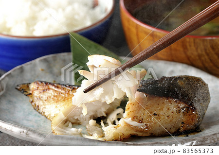 脂が乗って美味しそうな焼き目のついた銀鱈の西京焼きとほかほかご飯と熱々の味噌汁の朝食セットを食べる 83565373