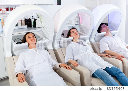 Clients of beauty salon relaxing on massaging chairs Clients of beauty salon relaxing on massaging chairs 83565403