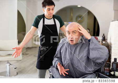 Dissatisfied man with shaved head in barbershop 83565598