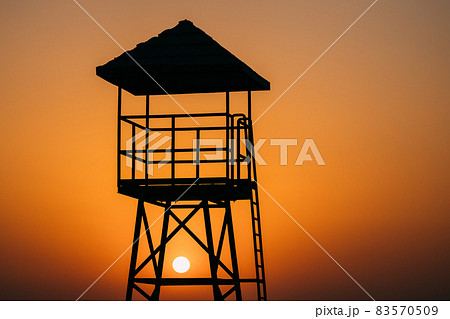 Lifeguard Tower Silhouette On Beach At Sunset. Sun Sunshine Through Lifeguard Tower At Summer Sunrise Sunset Lifeguard Tower Silhouette On Beach At Sunset. Sun Sunshine Through Lifeguard Tower At Summer Sunrise Sunset 83570509