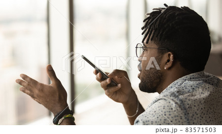 Young multiracial man recording audio message on cellphone. Young multiracial man recording audio message on cellphone. 83571503