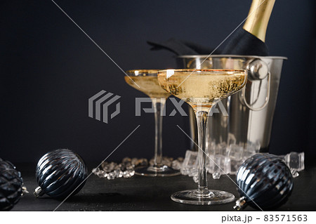 New Year champagne in wine glasses and bottle in bucket decorated Christmas blue baubles. 83571563