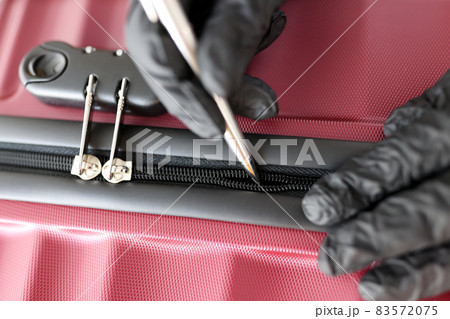 Gloved hands mending a snake on a suitcase Gloved hands mending a snake on a suitcase 83572075