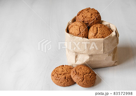Fresh oatmeal cookies in a bag made of paper on a white table background. Copy, empty space for text Fresh oatmeal cookies in a bag made of paper on a white table background. Copy, empty space for text 83572998