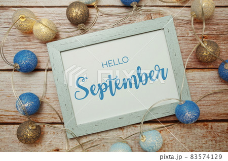 Hello September card typography text with LED cotton ball on wooden background Hello September card typography text with LED cotton ball on wooden background 83574129