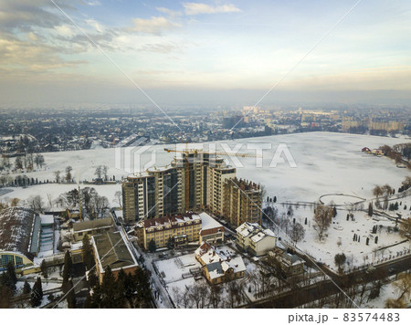 Apartment or office building under construction, aerial view. Tower crane silhouette on blue sky copy space background. Apartment or office building under construction, aerial view. Tower crane silhouette on blue sky copy space background. 83574483