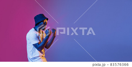 Winning success happy man celebrating being a winner. Dynamic image of male model on gradient purple pink studio background in neon 83576366