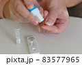 The woman uses a lancing device to take a blood sample from her finger 83577965