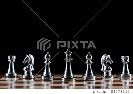 Silvery chess figures standing on chessboard Silvery chess figures standing on chessboard 83578116