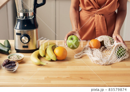 Hands of young housewife taking fresh fruits out of bag Hands of young housewife taking fresh fruits out of bag 83579874