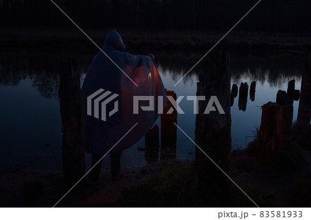 Man holding the old lamp outdoors near the lake. Hand holds a large lamp in the dark.  Ancient kerosene lantern illuminates the way on a night. Light and hope concept. 83581933
