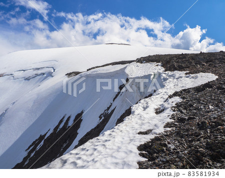 Dangerous snow ledge on the top of the mountain. Ledges from the snowy mountains. Cliffs and large rocks. Dangerous terrain. 83581934